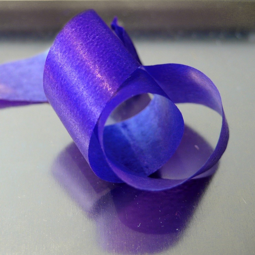 Brillant rosé et scintillement à la surface d’un ruban de papier texturé bleu, et reflet anisotrope sur le support en métal brossé. © Mathieu Hébert